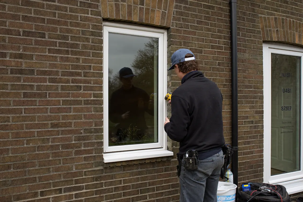 Fitter lifting a new casement window into place on a bay-fronted brick terraced house