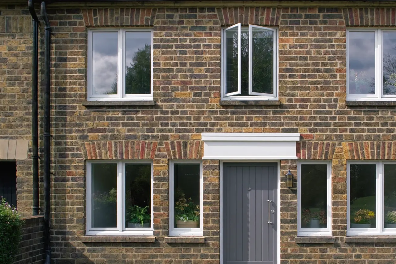 Bay-fronted brick home with all-new white windows and a matching front door after replacement