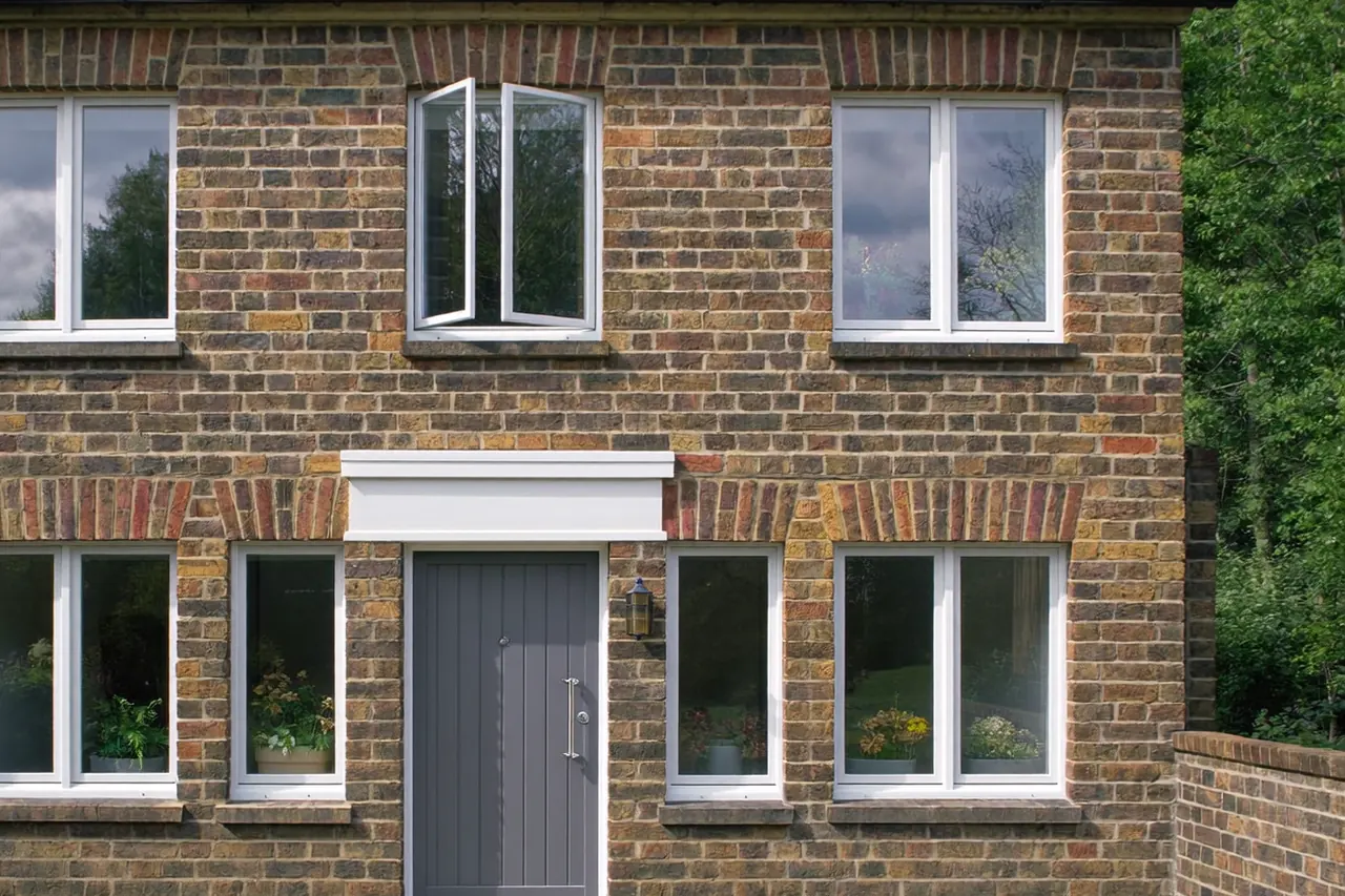 A white uPVC front door and a grey composite front door shown side by side on brick homes
