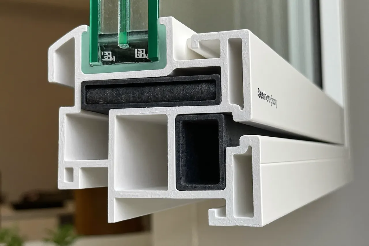 Close-up of a white uPVC window frame profile showing the multi-chamber section and rubber seal