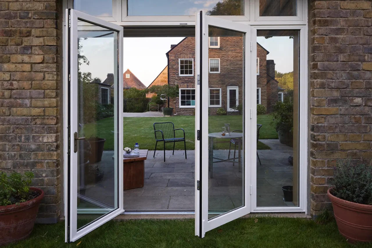 White French doors opened onto a paved patio at the rear of a brick family home